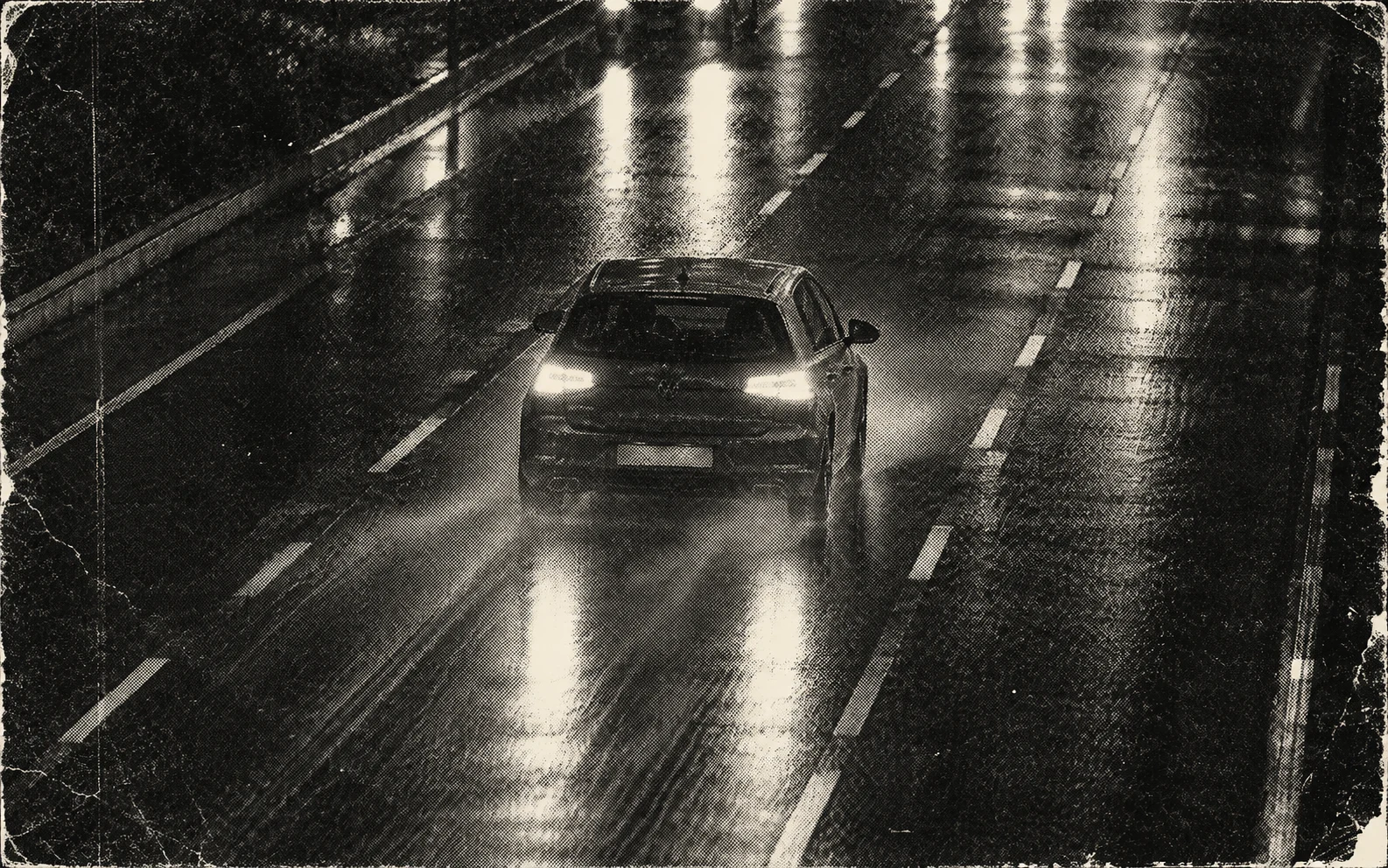 Rear view of a hatchback driving down a wet road at night, monochrome